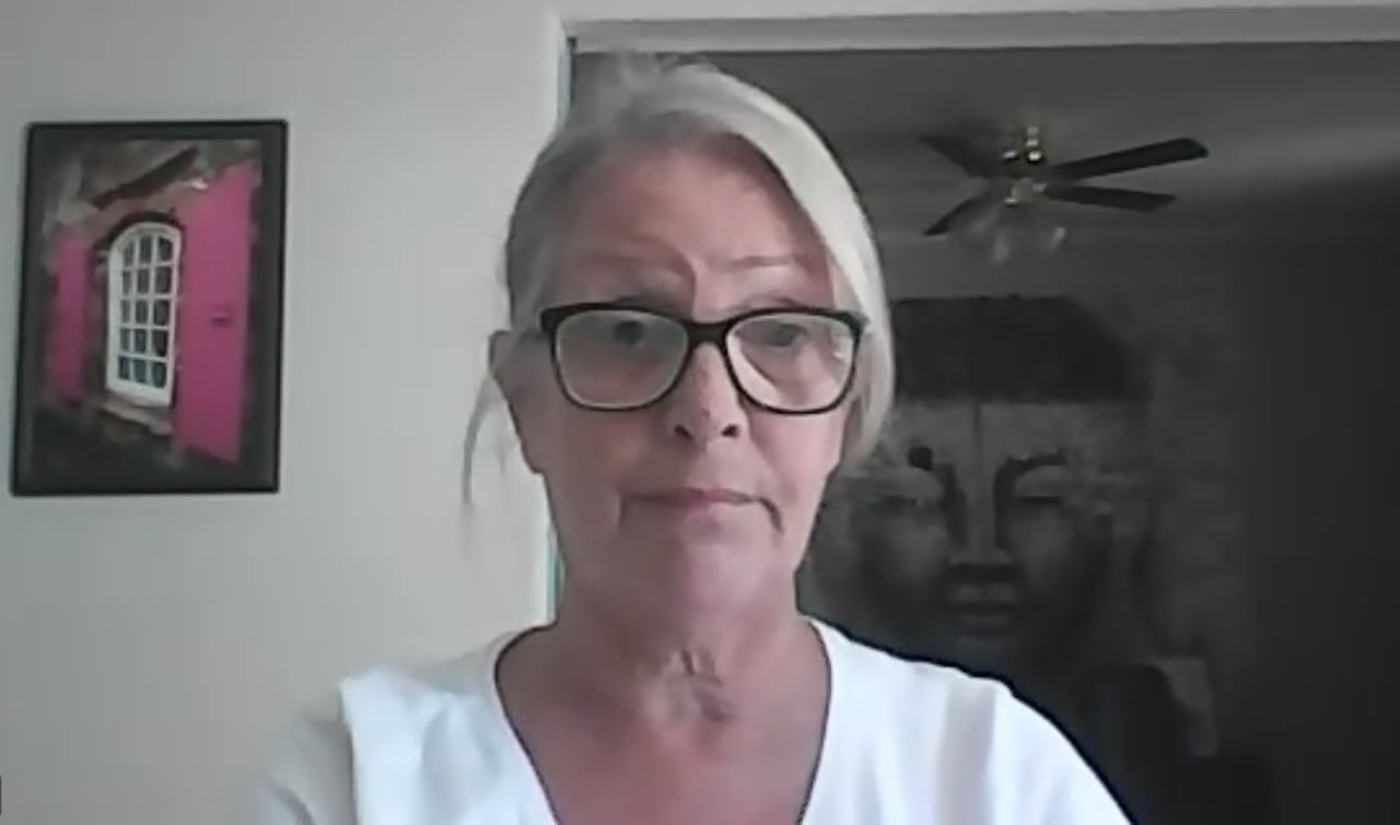 A woman with white hair and glasses