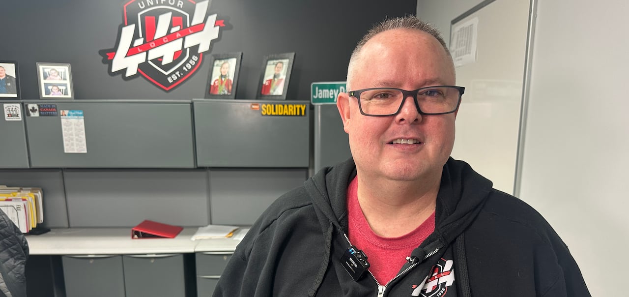 A man in a black hoodie looks at the camera