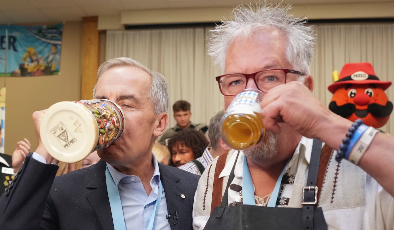 Two men drink from beer steins