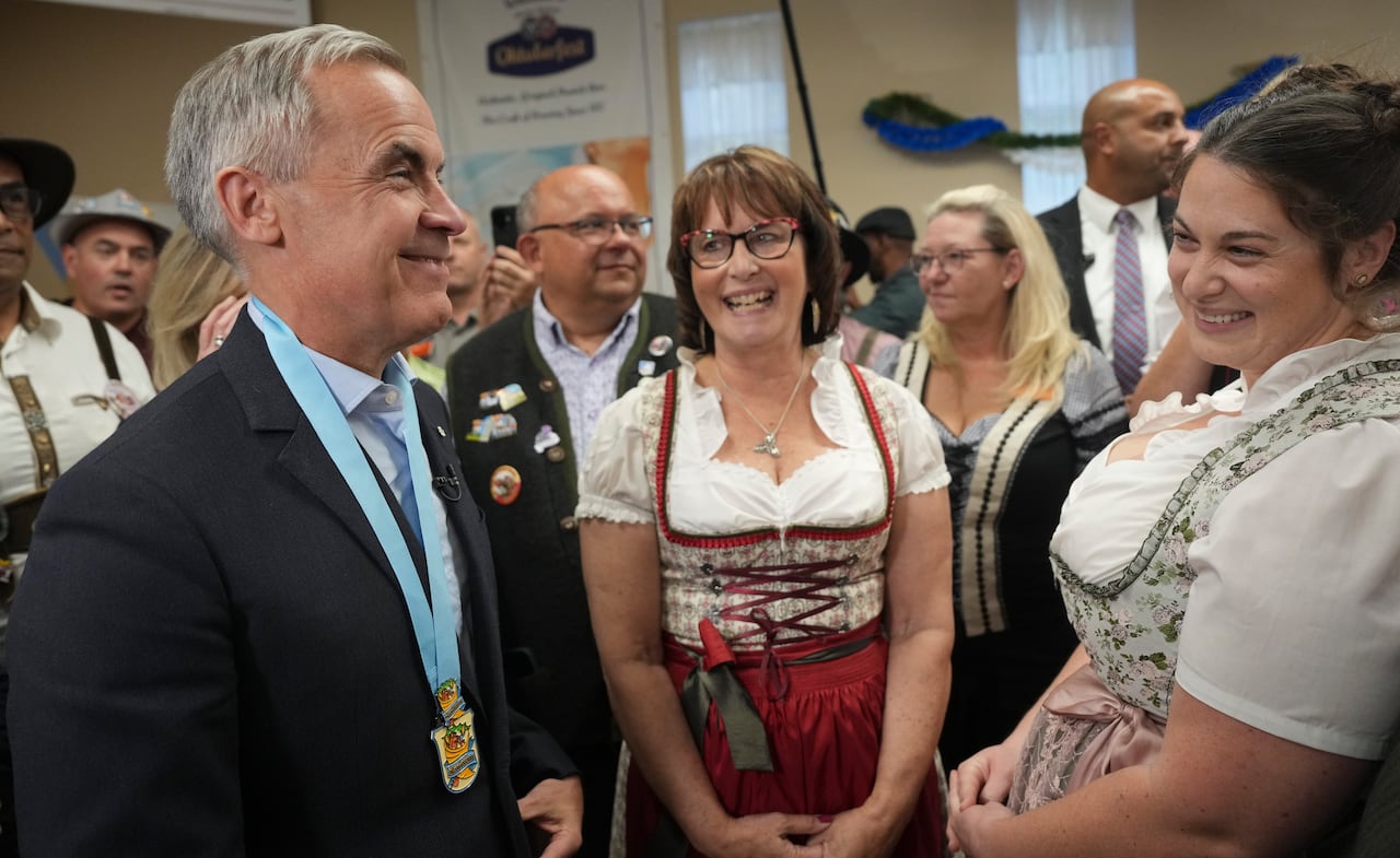 man talks to two ladies in dirndls
