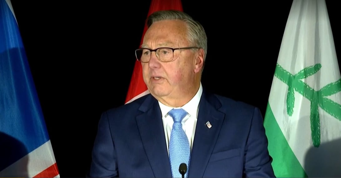 A man in a blue suit with a blue tie appears on stage.