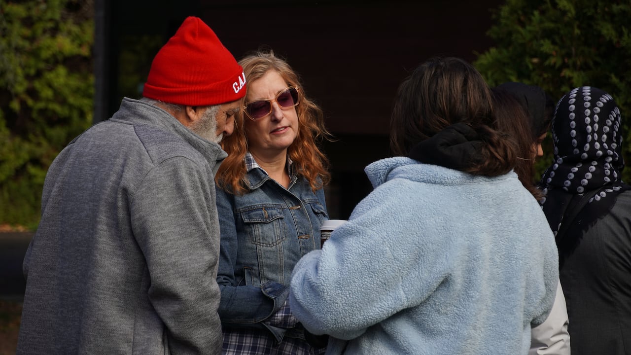 Woman speaks to another woman and a man.