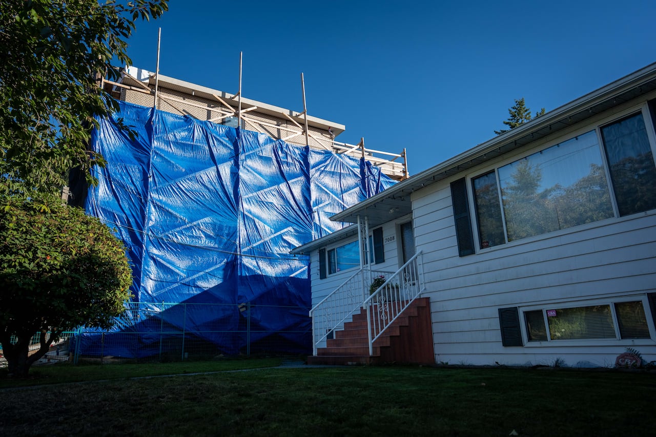 A large multiplex home under construction casts a shadow on its next-door-neighbour bungalow