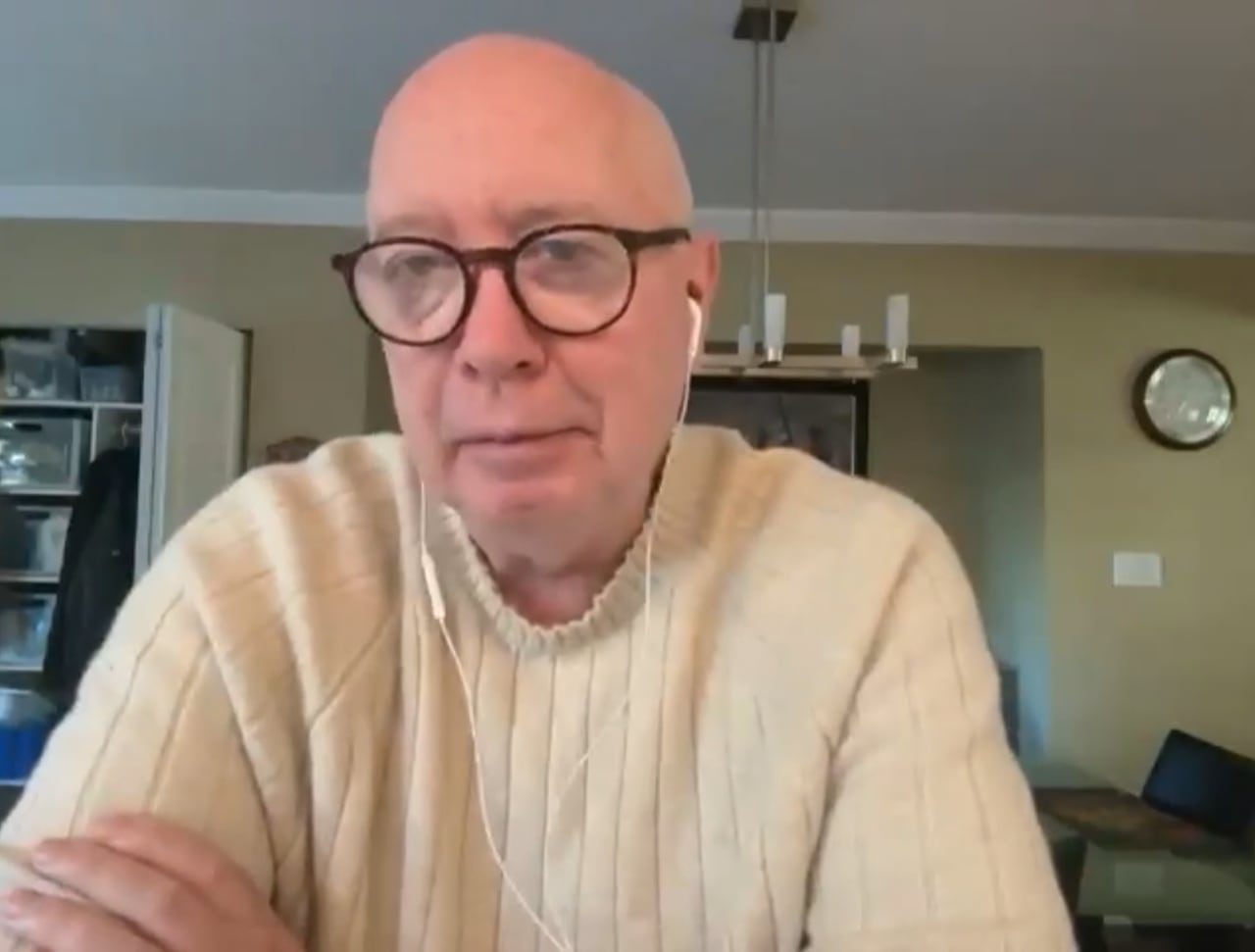 A man speaks on a Zoom call at home with headphones in