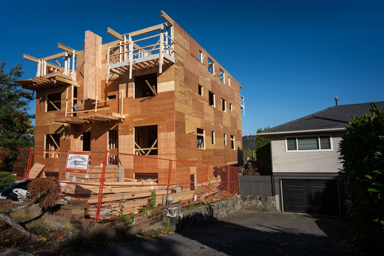 A multiplex home under construction next to a bungalow