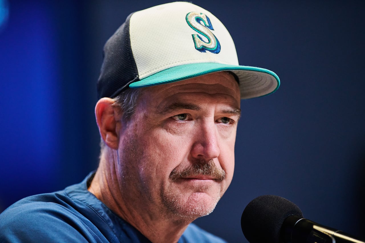 A man in a baseball cap, sitting in front of a microphone