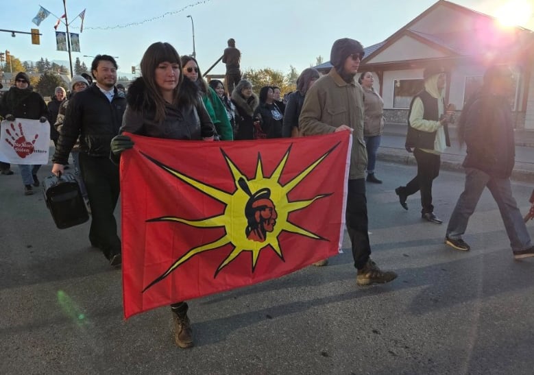 Two people hold a warrior flag while marching.