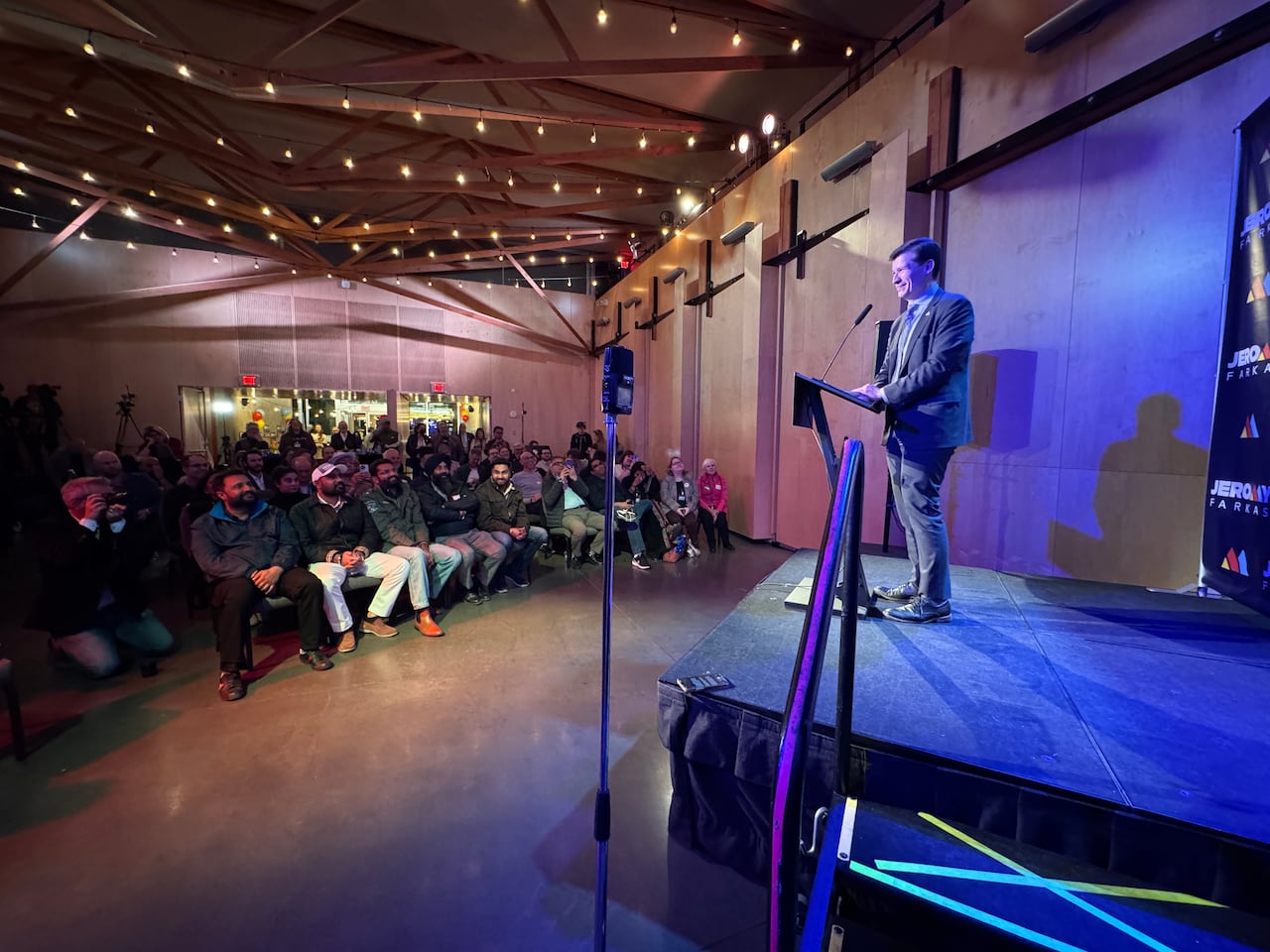 A man stands behind a microphone on a podium.