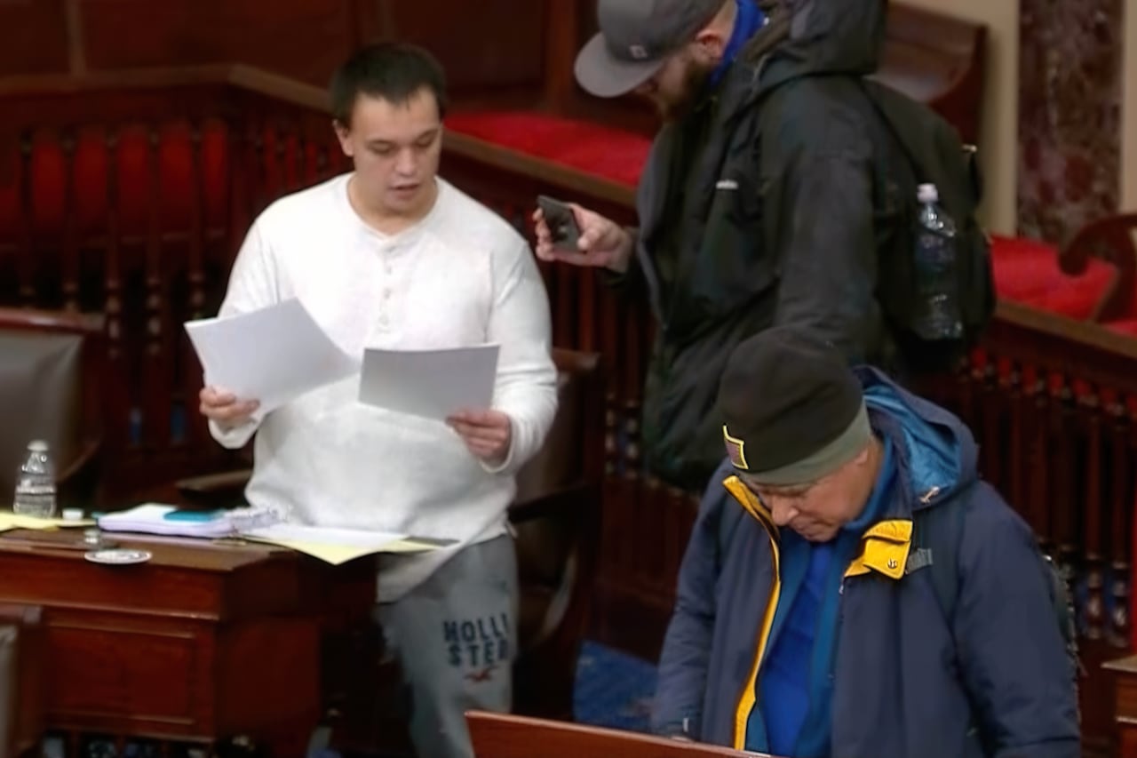 Man in white top looks at documents 