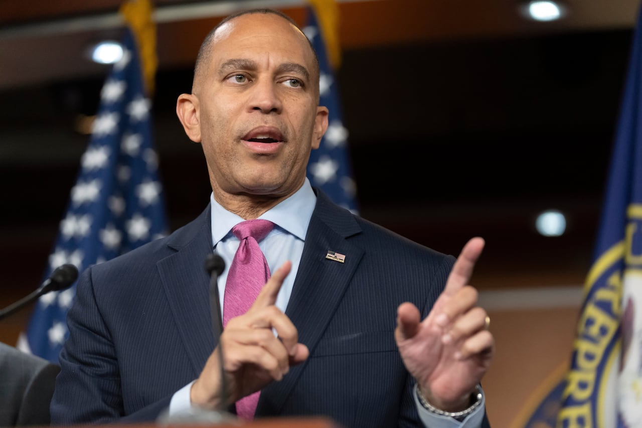 Man with short dark hair in dark suit gestures as he speaks