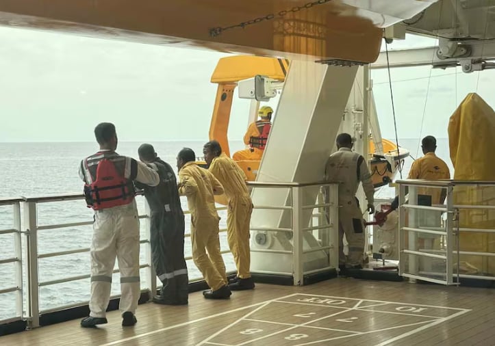Ship crew look over a railing