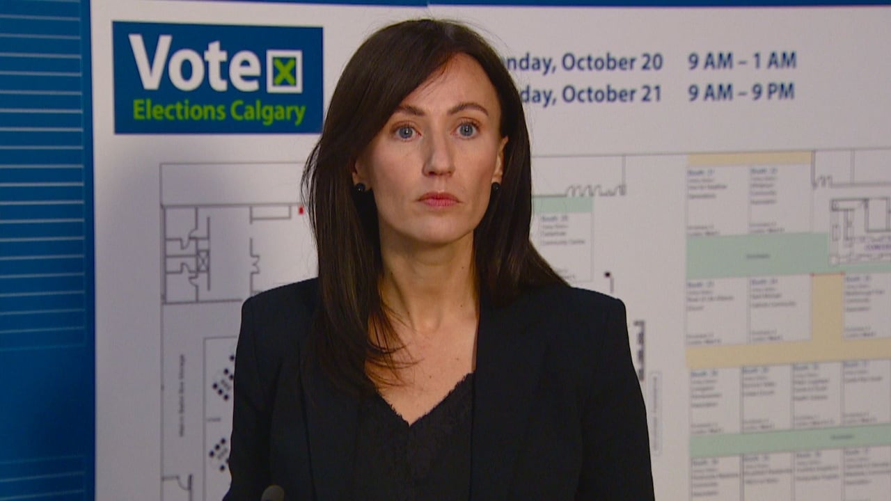 A woman stands in front of an Elections Calgary backdrop.