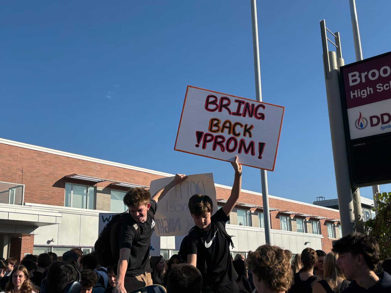 High school students holding a sign that reads, Bring Back Prom