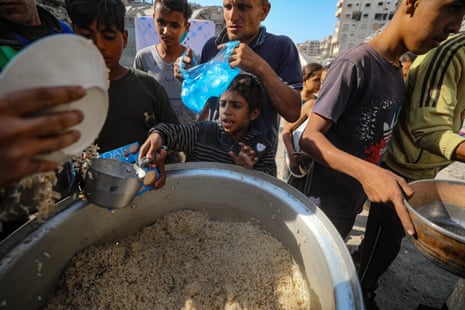Palestinians receive food from a charity kitchen, in Gaza City, on Thursday.