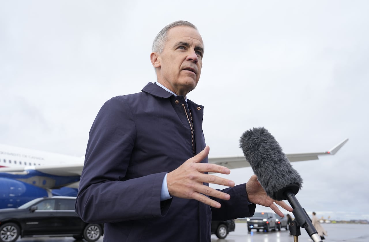 Carney stands at a microphone.