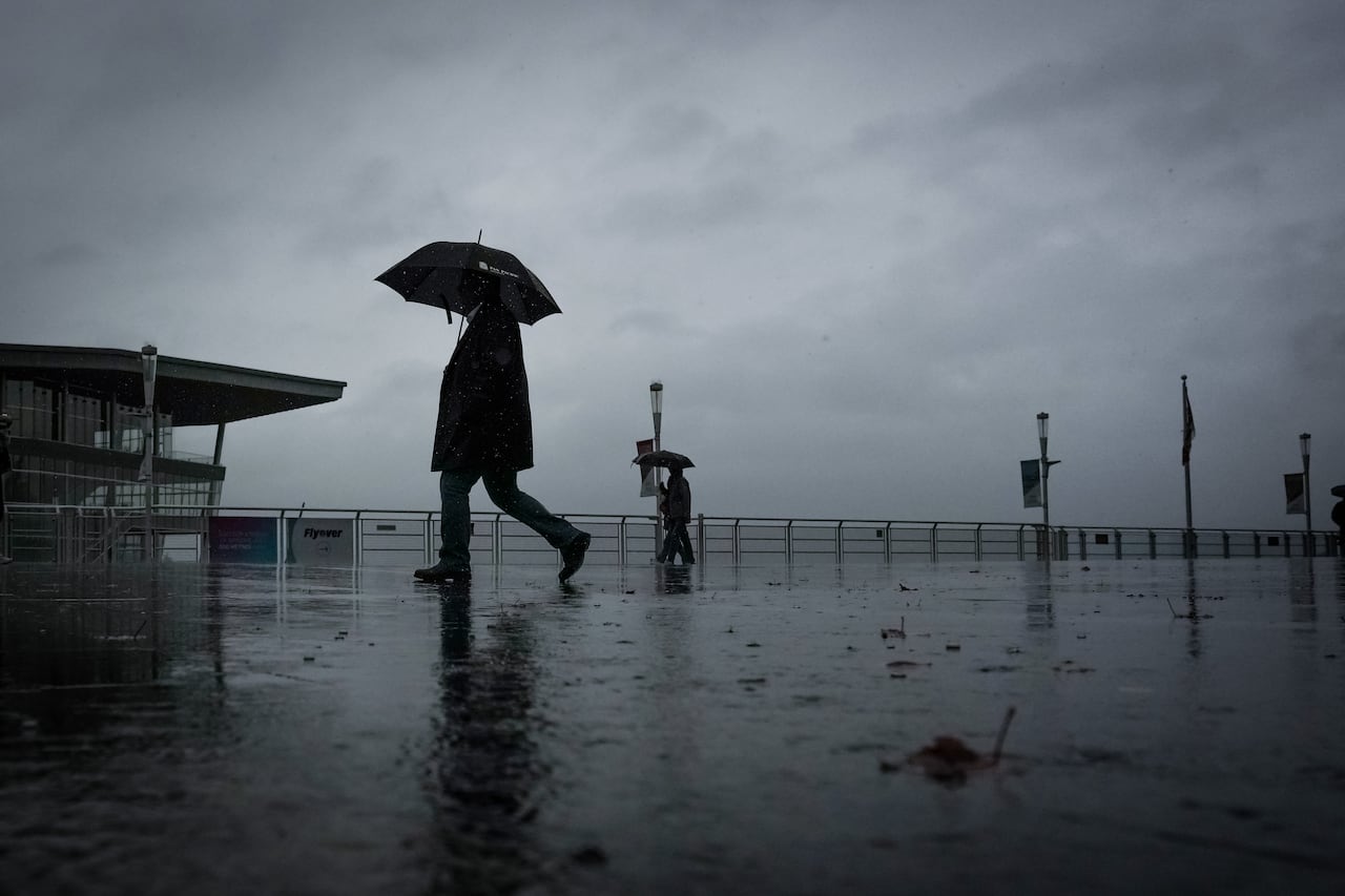 Two people walk by on a dark, rainy day holding umbrellas.