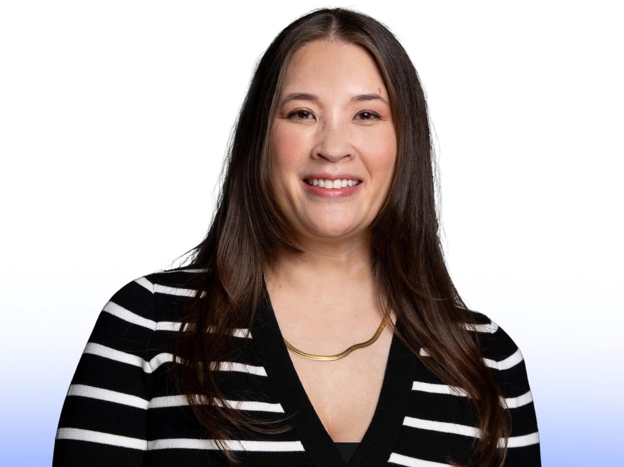 A woman in a black and white striped sweater smiles 