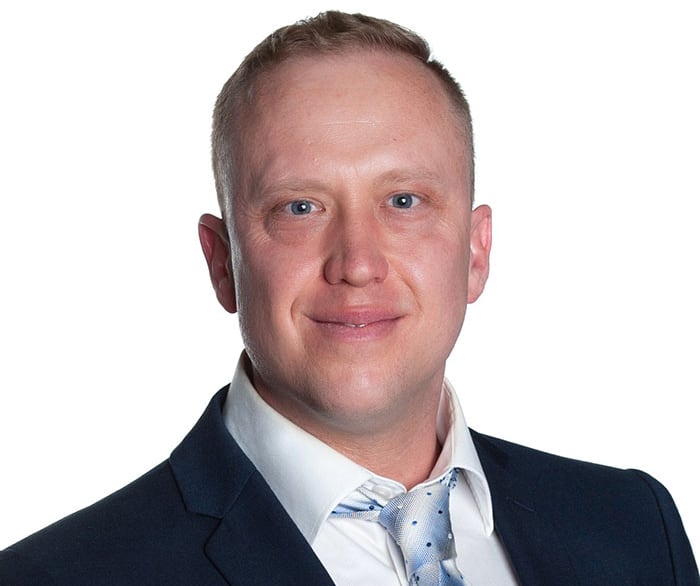 A man in a blue suit smiles at the camera
