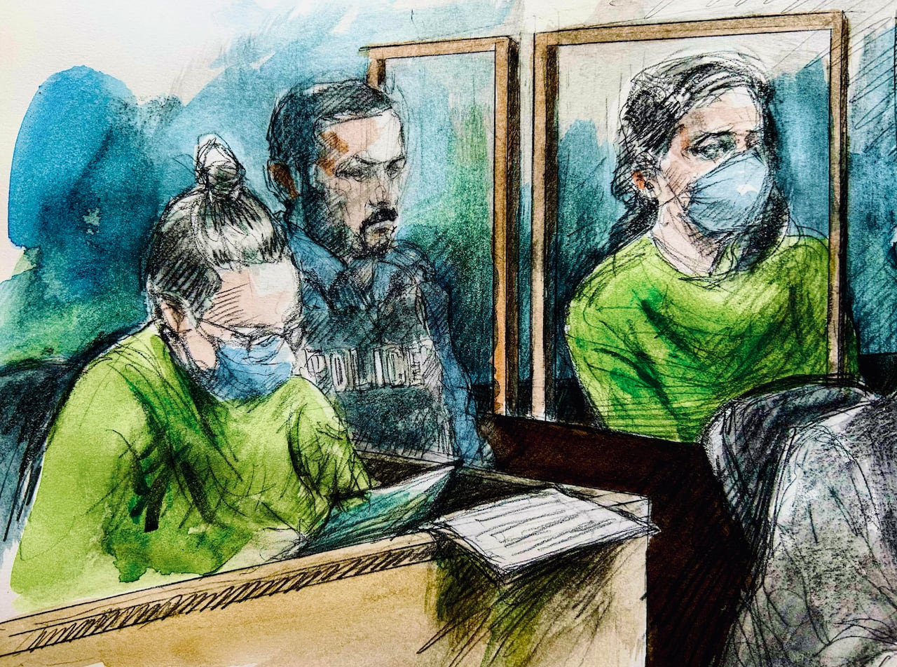 A court sketch showing two women in green prison jumpsuits seated in boxes with a police officer in-between them.