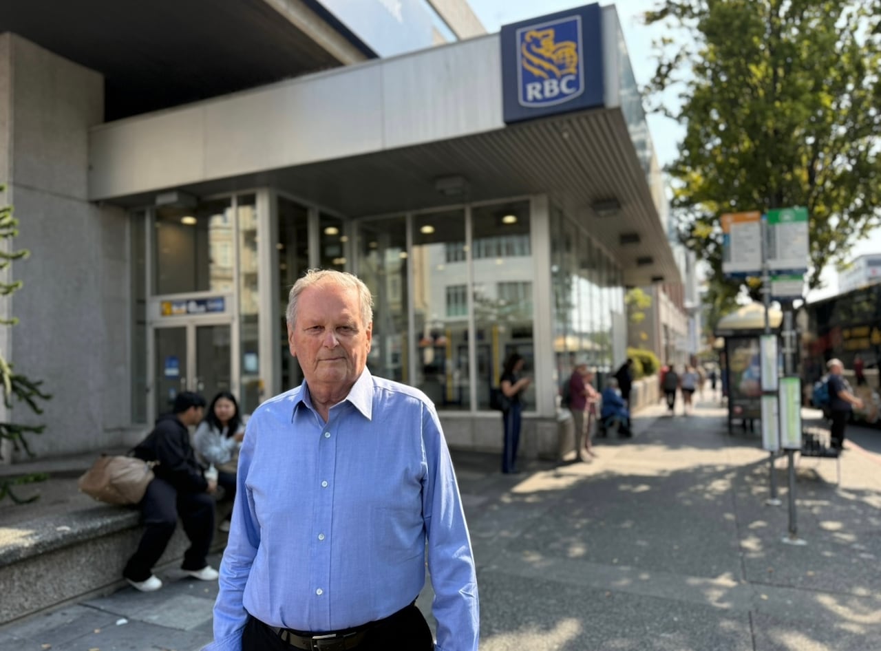 Elderly man standing outside a bank 