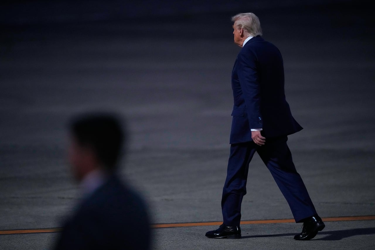 A man in a suit is shown from behind as he walks on an airport tarmac.