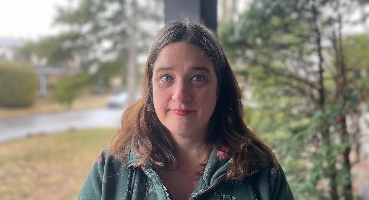 A brunette woman stands on a porch.