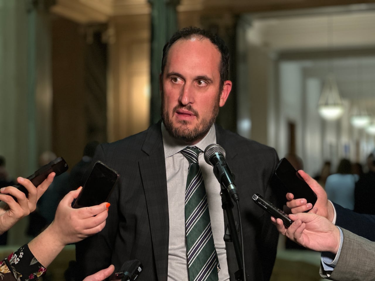 A man in a dark suit speaks into a microphone.