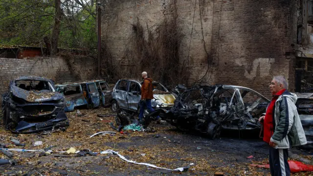 Residents inspect cars which were destroyed during an overnight Russian drone strike, amid Russia's attack on Ukraine, in Kyiv