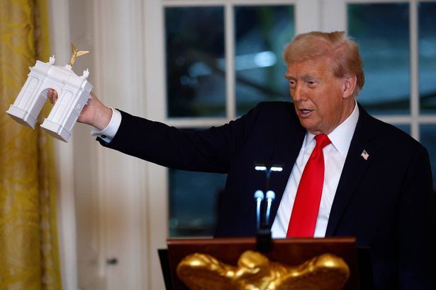 U.S. President Donald Trump holds a model of an arch 