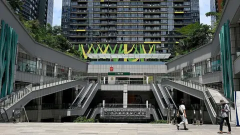 AFP via Getty Images People walk past the Prince International Plaza in Phnom Penh on October 15, 2025. 