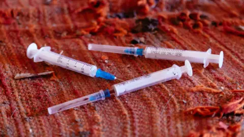 Getty Images Three syringes, seemingly used, lying on a tattered orange blanket