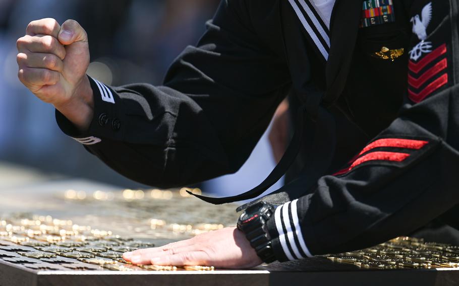 A Naval Special Warfare Operator stamps a trident onto a wooden plaque