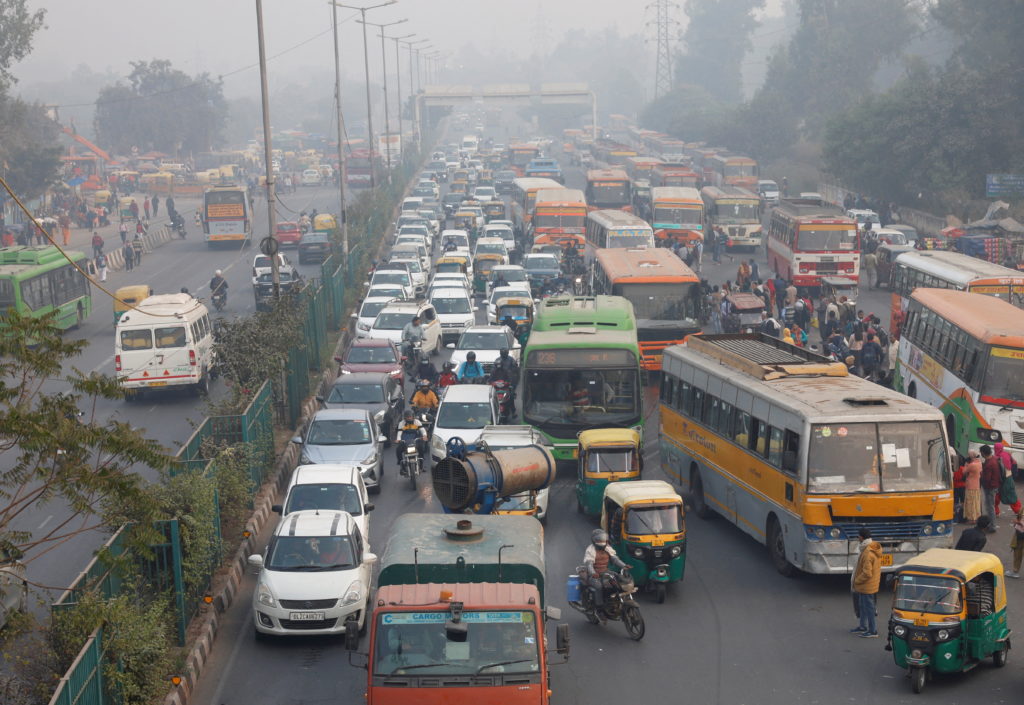 An anti-smog gun sprays water to settle dust particles as traffic moves along a road
