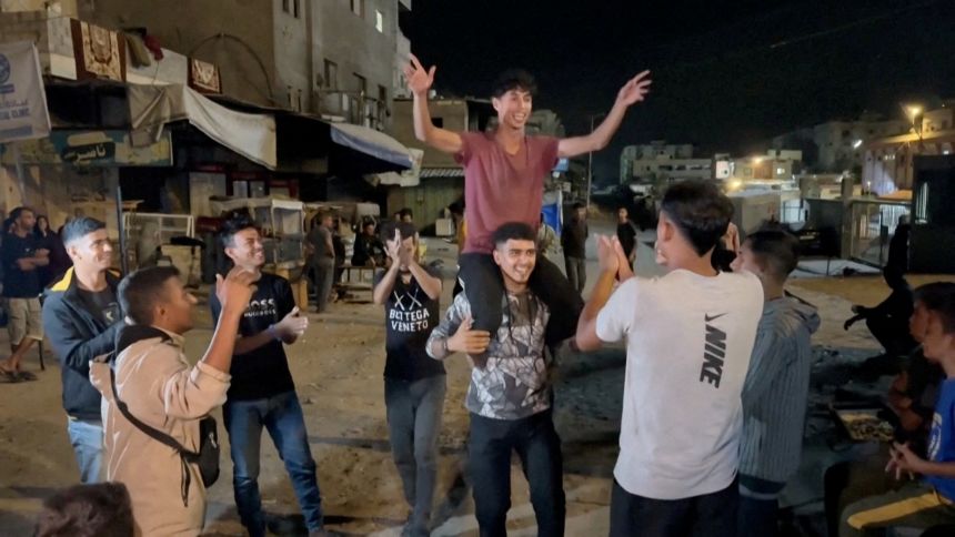 Palestinians celebrate on a street following the news that Israel and Hamas have agreed to the first phase of a ceasefire plan, in Khan Younis in southern Gaza, in this screengrab obtained from a video released on October 9, 2025.