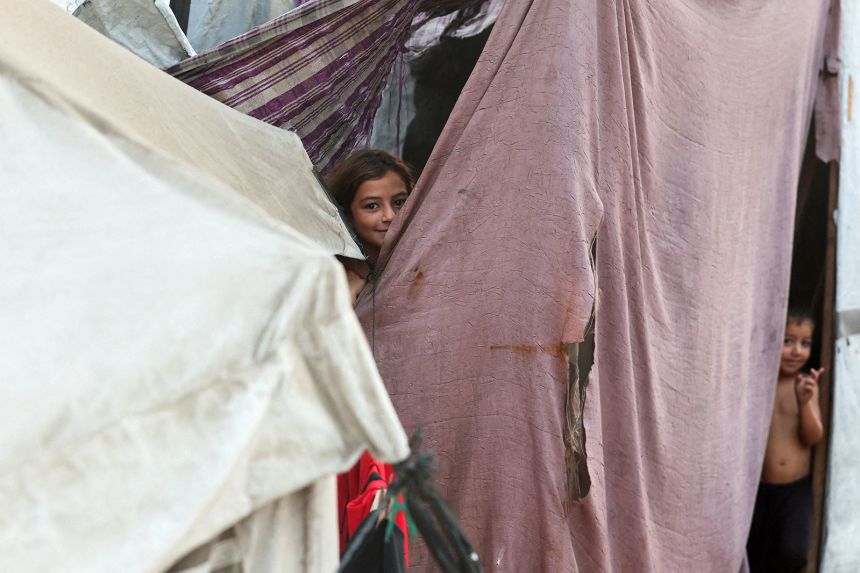 A Palestinian girl sheltering at a tent after US President Donald Trump announced that Israel and Hamas agreed on the first phase of a Gaza ceasefire, in Khan Younis in southern Gaza, on October 9, 2025.