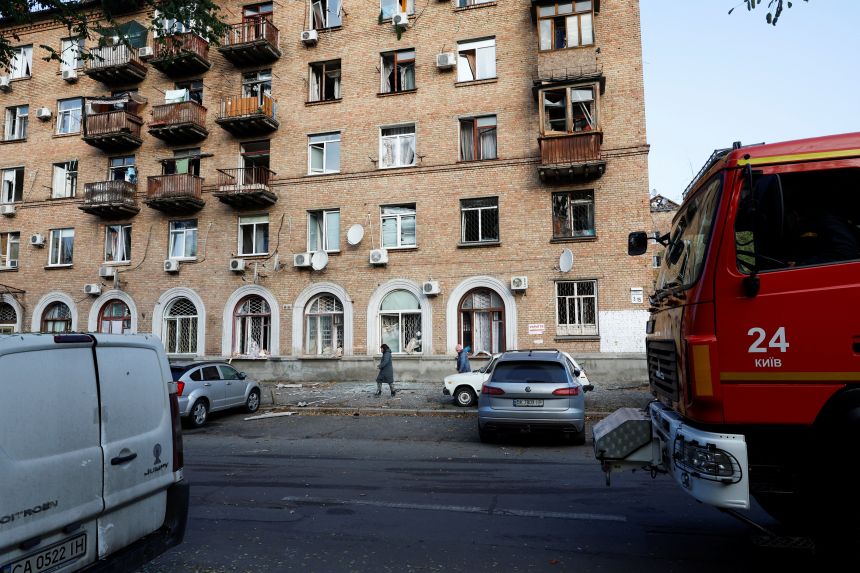 People walk past residential buildings damaged during a Russian drone and missile strike, amid Russia's attack on Ukraine, in Kyiv, on October 22, 2025.