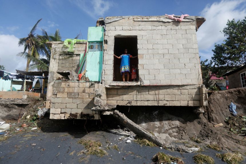 A woman looks out from inside a house in Alligator Pond, Jamaica, on Wednesday.