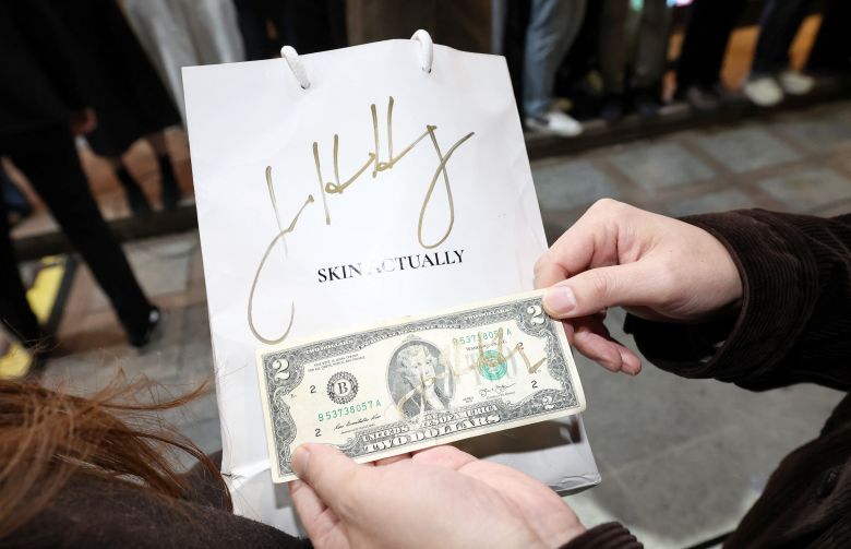 A man shows an autograph of Nvidia CEO Jensen Huang as he arrives for a dinner meeting with Samsung Electronics Chairman Jay Y. Lee and Hyundai Motor Group Executive Chair Euisun Chung at a fried chicken restaurant in Seoul, South Korea, on October 30, 2025.
