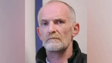 BBC Man with shaved head and goatee beard wearing coat