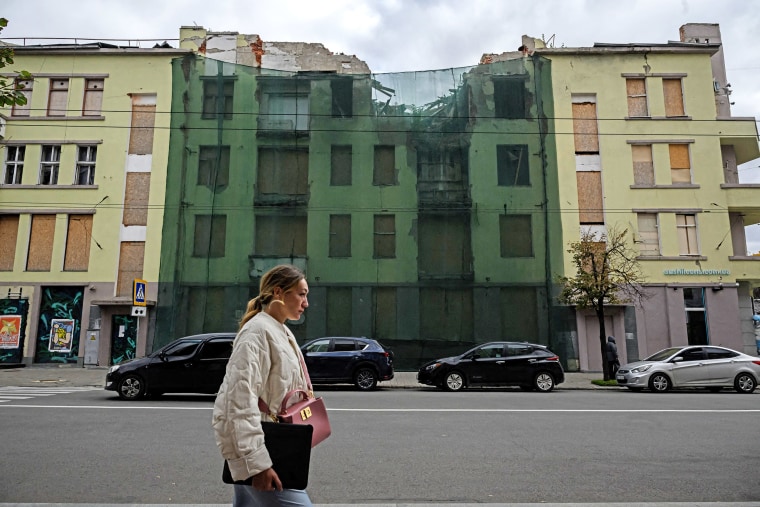 A pedestrian walks past a building damaged by a Russian strike