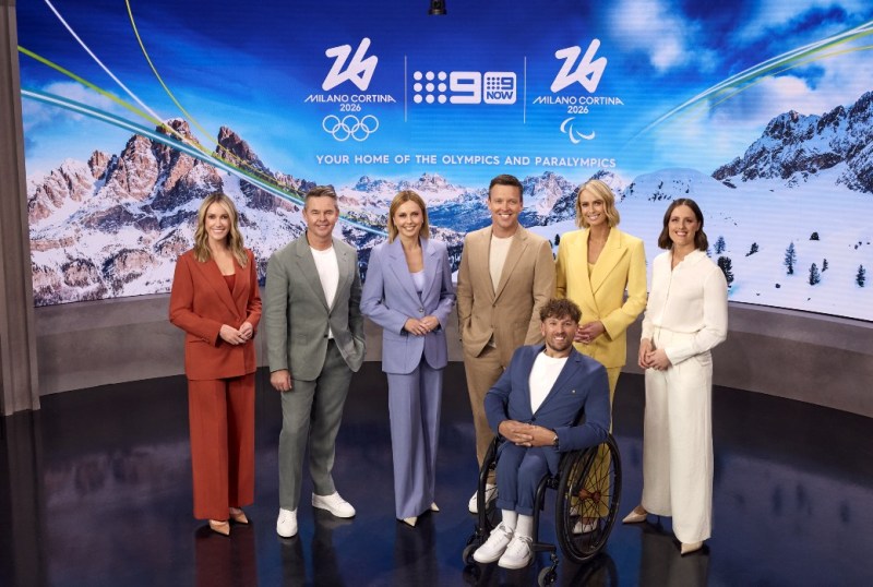 Group of presenters for the 2026 Milano Cortina Olympics and Paralympics, standing in a studio with a snowy mountain backdrop, promoting 9Now as the home of the Games.