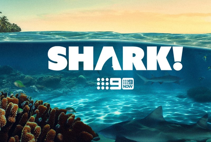Promotional image for the show "Shark!" featuring vibrant underwater scenery with coral and fish, highlighting the ocean environment. Logo includes "9 NOW" for streaming availability.