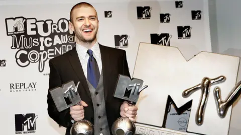 Getty Images Justin Timberlake smiling and holding two MTV Europe Music Awards alongside a giant MTV logo at the MTV Europe Music Awards 2006 in Copenhagen