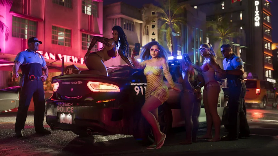 A vibrant street scene with neon lights. A police car is surrounded by people in colorful outfits, with two officers nearby.