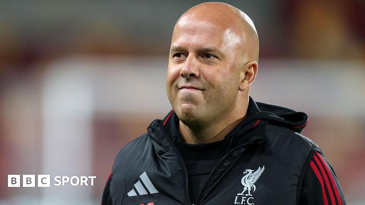 A wide shot of a child looking on at a selection of Liverpool scarves.
