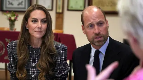 Getty Images William and Kate sat down facing an elderly woman who is talking to them. 
