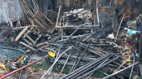 Higham Ferrers Riverside Angling Association Burnt and damaged items, inside a storage container, on the floor, all charred and damaged. 