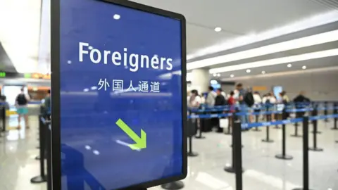 Getty Images A sign at a Chinese immigration checkpoint says "foreigners", with an arrow pointing to a lane for foreign visitors