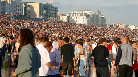Getty Images Thousands of music fans are packed tightly on Brighton beach and along the promenade.