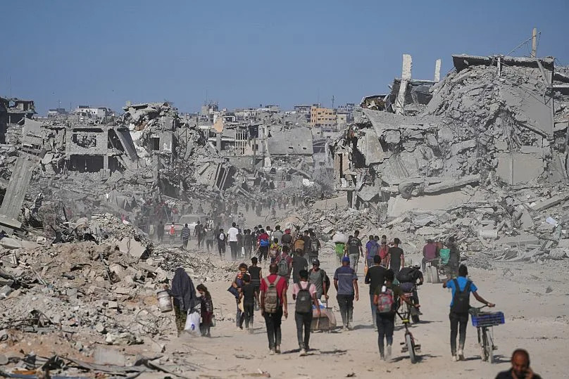 Displaced Palestinians pass by destroyed buildings as they return to their homes in the Zeitoun neighbourhood of Gaza City, 10 October, 2025